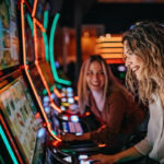 Girl friends gambling in casino on slot machinery